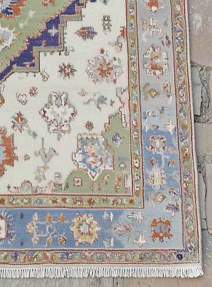 Terracotta Oushak wool rug with light blue floral and geometric patterns on a burnt orange background