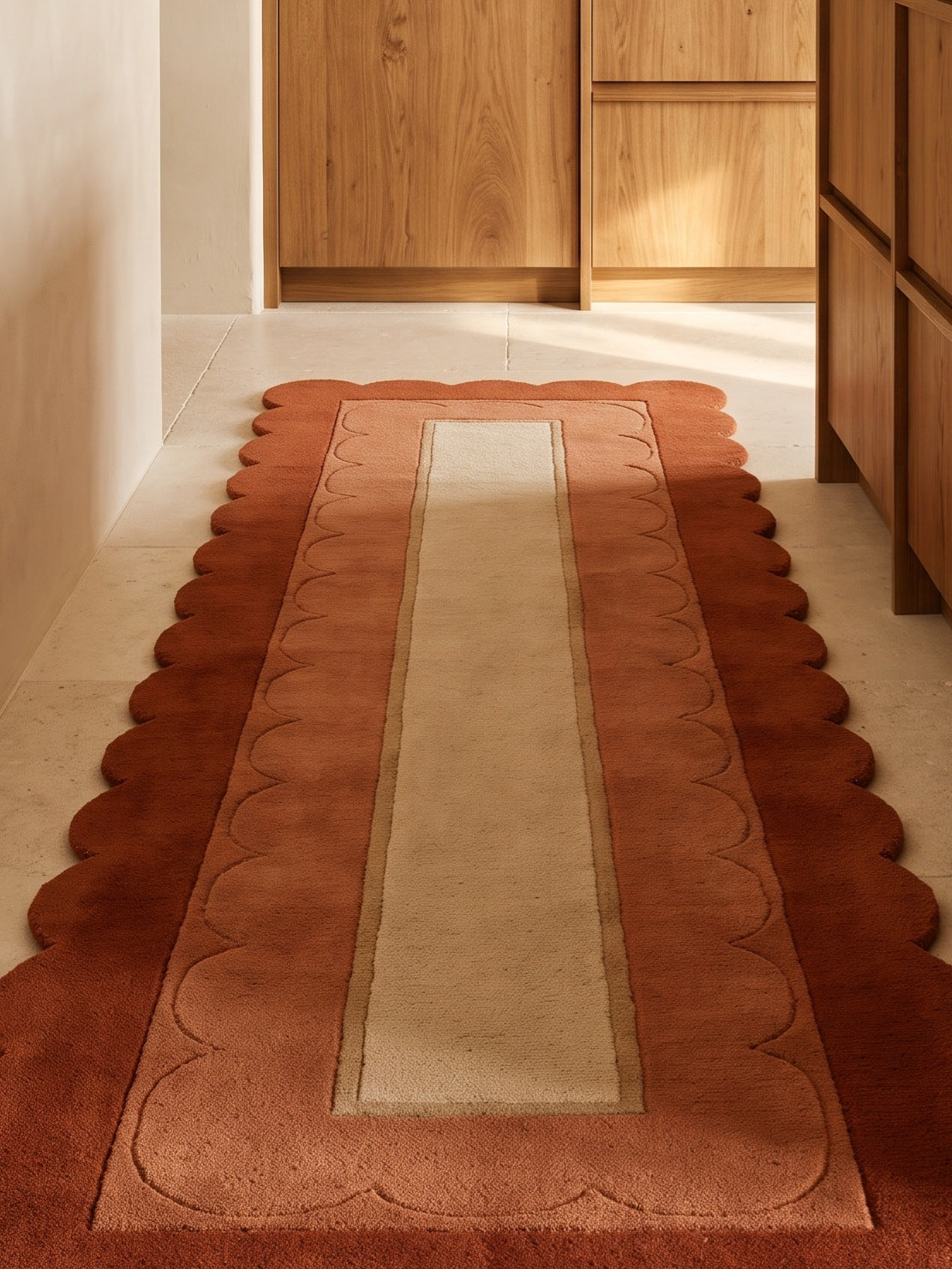 Terracotta Scalloped Runner Rug in rust and sand wool, with a deep rust scalloped edge and carved inner border
